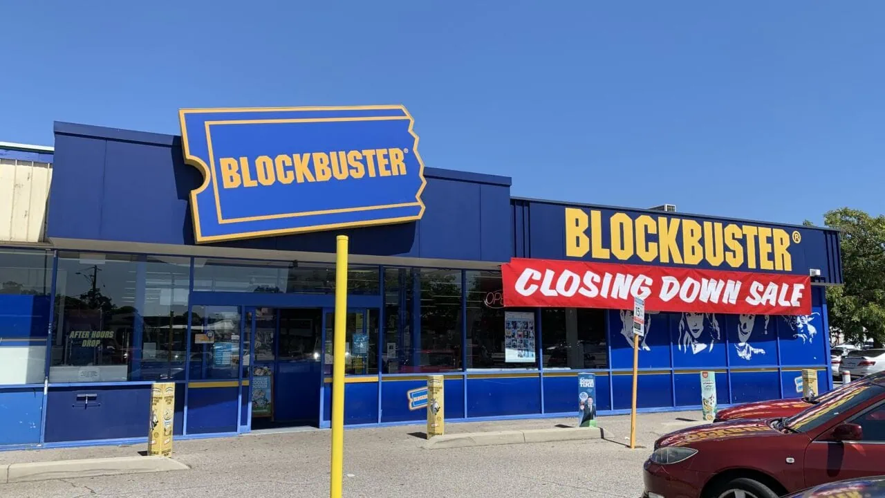 a store with a blue and yellow sign and cars parked in front of it