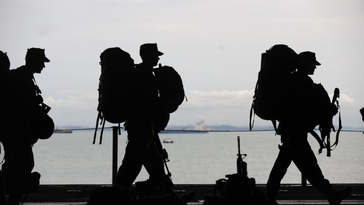 a group of people with backpacks walking next to a body of water a group of people with backpacks walking next to a body of water