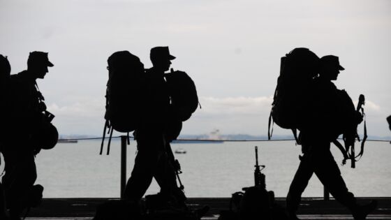 a group of people with backpacks walking next to a body of water