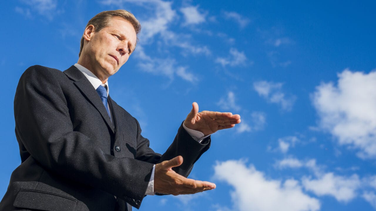 Low Angle View Businessman Presenting Something Against Blue Sky Low Angle View Businessman Presenting Something Against Blue Sky