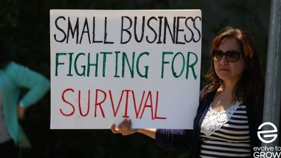 a woman holding a sign that says small business fighting for survival