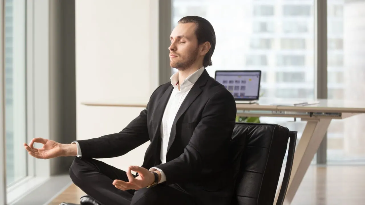 Successful Businessman Meditating At Workplace In Modern Office.